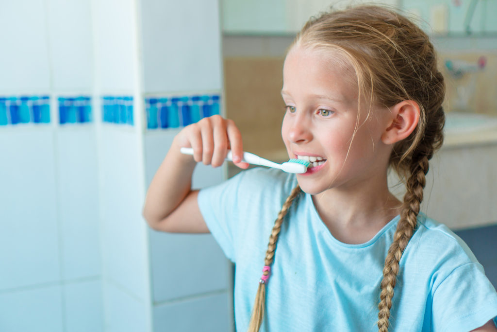 Dziewczynka szczotkująca zęby w łazience.